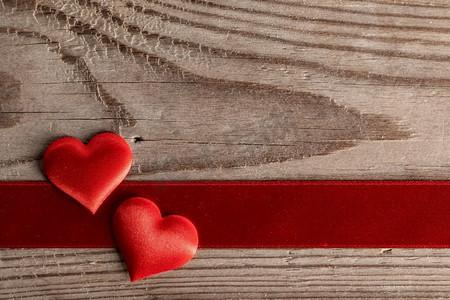 情人节两个红色丝绸心和丝带条纹在木背景，爱概念。’情人节心在木头