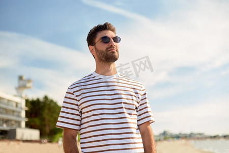 年轻人海边摄影照片_暑假和人的概念—年轻人的肖像在海滩太阳镜在塔林，爱沙尼亚。年轻人在夏天的海滩太阳镜