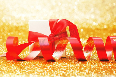白色礼品盒与红丝带蝴蝶结在金色闪光背景