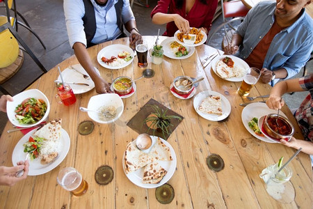 休闲，美食和人的概念—一群快乐的国际朋友在餐厅的餐桌上用餐。国际朋友在餐馆吃饭