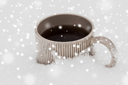 饮料，圣诞节和冬季假期概念—茶或咖啡杯在雪。雪中的茶或咖啡杯