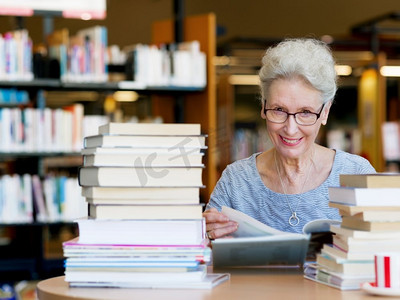 一位老妇人在图书馆看书。从容地读新书