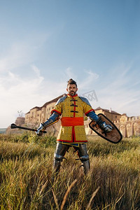 战士摄影照片_中世纪骑士在城堡对面的盔甲摆姿势，伟大的比赛。装甲古代战士在装甲摆在领域