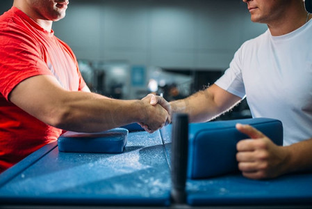 两个手臂摔跤手在战斗或摔跤比赛后握手，在背景的健身房内部摔跤挑战，力量运动