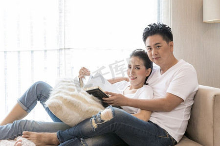 读书分享摄影照片_年轻夫妇在当代住宅客厅里一起读书，分享生活方式理念