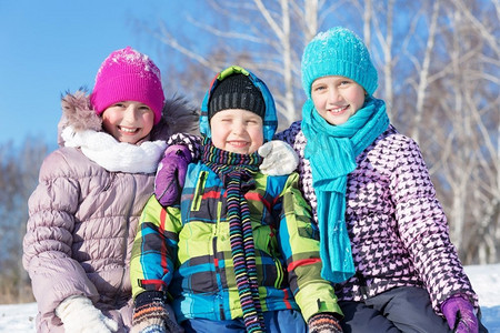 玩雪橇的孩子摄影照片_冬天的乐趣。三名儿童在美丽的雪地公园玩雪橇