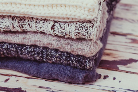 堆叠温暖的针织毛衣在白色和灰色的阴影。毛织品收藏