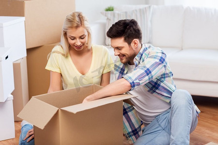 抵押贷款，搬家和房地产概念—快乐的夫妇开箱箱在新家。快乐的夫妇开箱箱在新家