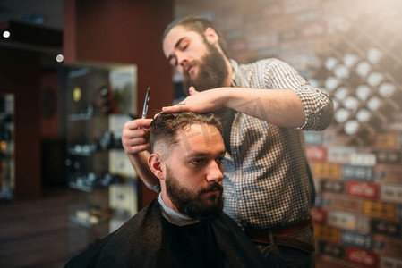 剪子剪发剪剪头发的顾客人在黑色沙龙斗篷，理发店在背景