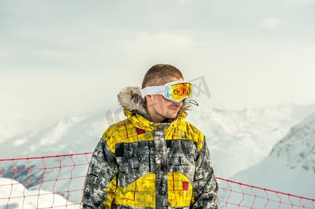 滑雪护目镜摄影照片_戴着滑雪护目镜的年轻人在户外，背景是法国阿尔卑斯山被白雪覆盖。Vald&rsquo；伊斯雷尔，法国