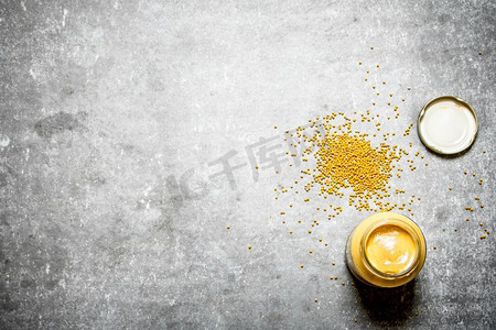 调味罐摄影照片_一罐新鲜芥末。在石桌上。一罐新鲜芥末。