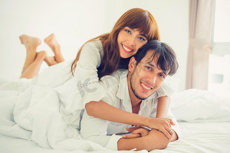 幸福的年轻夫妇早上醒来后在家里的卧室里放松。