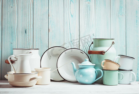 厨房桌子上的搪瓷器皿，上面是蓝色的木质墙壁。珐琅器皿静物