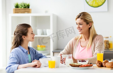 健康饮食，家庭和人的概念-幸福的母女在家中的厨房吃早餐。幸福的一家人在家里的厨房里吃早餐