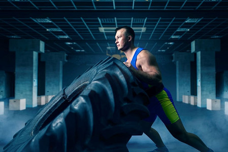 强壮的男性运动员做力量锻炼与卡车轮胎在体育馆，交叉健身锻炼。体育俱乐部的交叉健身训练