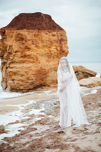 可爱的内裤摄影照片_新娘穿着内裤和睡袍，头戴面纱走在海滩上