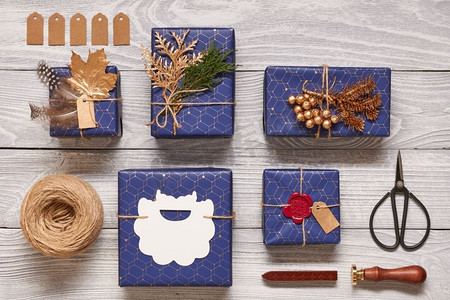 创意包装和装饰的圣诞礼物在白色木制背景的盒子里。从上面俯瞰。平躺着。