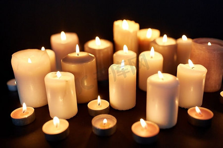 黑暗蜡烛摄影照片_哀悼和纪念概念-蜡烛燃烧在黑暗在黑色背景。蜡烛燃烧在黑暗中在黑色背景