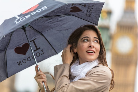 英国伦敦，带着一把背景是大本钟的我心伦敦雨伞度假的女孩或年轻女性游客
