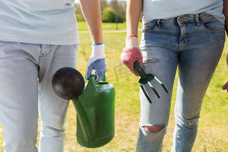 志愿服务、人和园艺概念-有喷壶和除草耙子的志愿者夫妇。志愿者拿着喷壶和除草耙