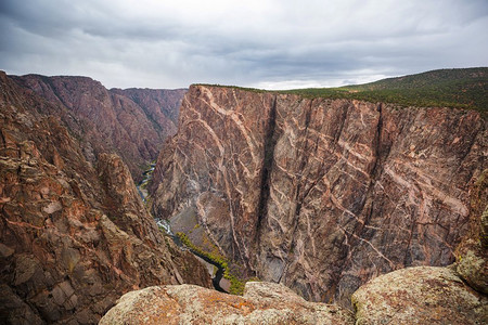 甘尼森摄影照片_游客在美国科罗拉多州甘尼森黑峡谷的花岗岩悬崖上