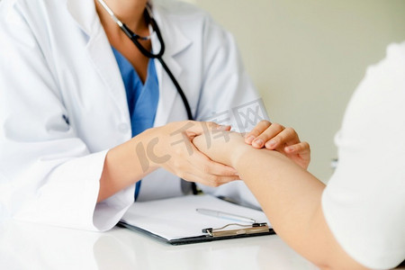 女医生在医院办公室与女病人交谈，手把手检查病人的脉搏。医疗保健和医疗服务。