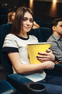 一名年轻女子在电影院看电影时吃爆米花。表演时间到了。一名女子在电影院看电影时吃爆米花