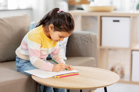 童年、创造力与艺术理念--小女孩在家中用彩笔作画。小女孩在家里用彩色铅笔画画