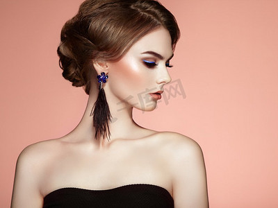 广告化妆摄影照片_美丽的女人与大耳环流苏珠宝黑色颜色。完美的化妆和优雅的发型。蓝色化妆箭头