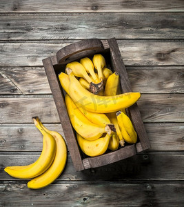 很多香蕉放在一个黑色的木箱里。在一个黑色的木背景。很多香蕉放在一个黑色的木箱里。