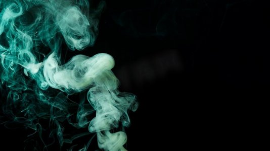 抽象烟雾摄影照片_抽象绿烟移动黑色背景。漂亮的照片。抽象绿色烟雾移动黑色背景