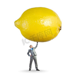 维生素对健康。年轻健康的商人解除巨大的柠檬以上的头部