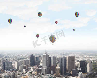 飞翔的气球。五颜六色的浮空器在现代城市上空的晴空中飞舞