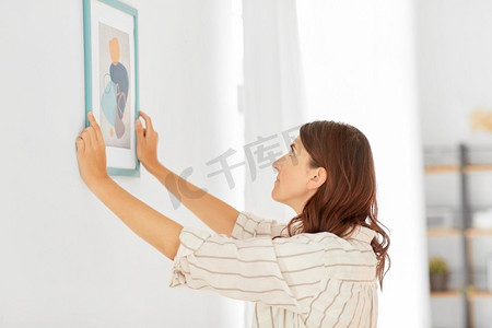 家居装修，装饰和人的概念—妇女挂在墙上的框架图片。妇女装饰家庭与图片框架