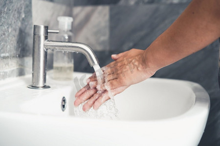 冠状摄影照片_洗手以预防新型冠状病毒病2019或COVID—19。人们在洗手池洗手以清除病毒感染。