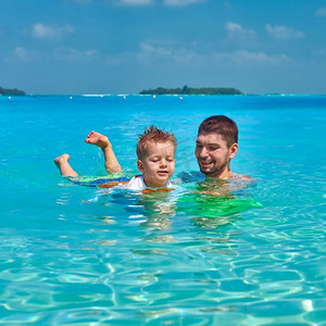 三岁的学步男孩和父亲一起学习游泳。暑假全家去马尔代夫度假。