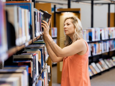 一名妇女在公共图书馆挑选一本书。这是一个艰难的选择