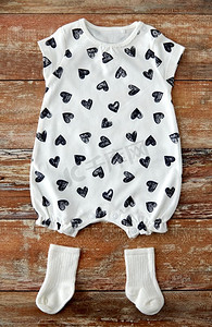 婴儿衣服，婴儿时期和服装概念—紧身衣女孩有心脏印和袜子在木桌上。婴儿紧身衣和袜子在木桌上