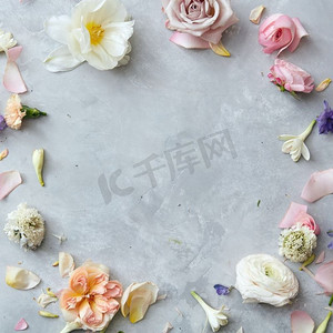 玫瑰花框摄影照片_灰色混凝土背景上有玫瑰和花瓣的花框。玫瑰花框