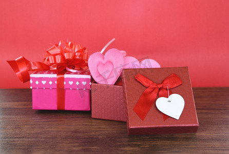 情人节礼物盒红色和粉红色在木背景和粉红色心在盒子爱概念和礼物盒丝带弓在红色背景