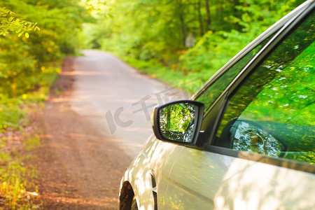 银色的汽车站在路边的道路在树林里。侧视图。在树林里开车