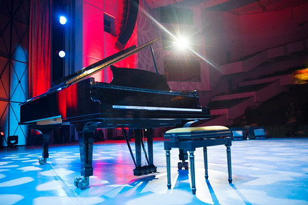 舞台炫酷光摄影照片_聚光灯下舞台上的钢琴。在音乐会之前