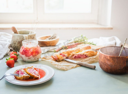 美味的草莓大黄馅饼蛋糕在阳光明媚的厨房桌子与成分在窗口。自制季节性美食