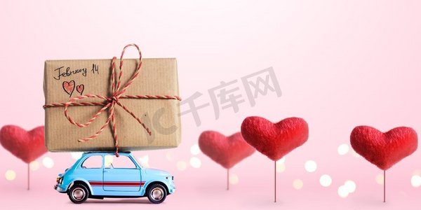 蓝色复古玩具车送货礼盒，2月14日情人节标题，粉色背景，心形树