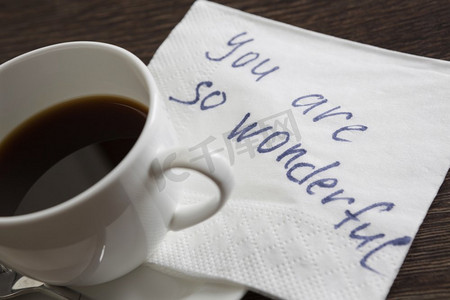 咖啡纸巾摄影照片_我喜欢纸巾上的忏悔。纸巾和木桌上的一杯咖啡上写着浪漫的信息
