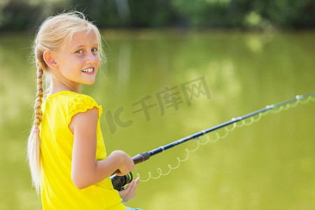我要钓大鱼！肖像可爱的女孩坐在银行和钓鱼