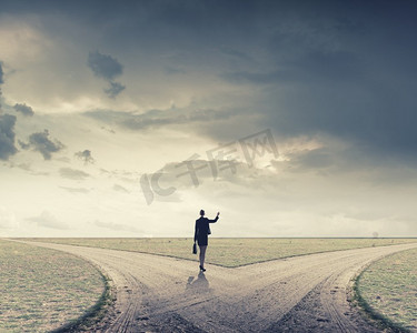 站在十字路口做出选择的女商人的背影.沙漠天空