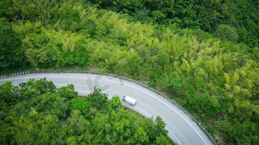 空中俯瞰森林自然与公路上的山上绿树为背景，俯瞰亚洲乡村上方的道路曲线