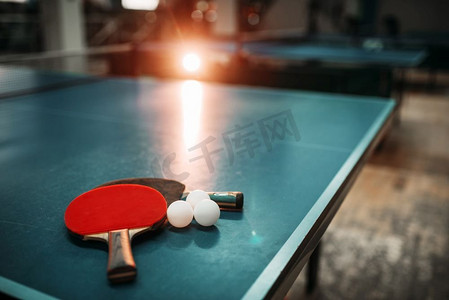 乒乓球桌与球拍和球在一个运动大厅，游戏设备。室内网球俱乐部。乒乓球桌，球拍和球在体育馆