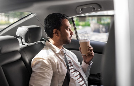 运输，企业和人的概念—印度人与外卖咖啡在后座在出租车汽车。印度男子与外卖咖啡在汽车后座